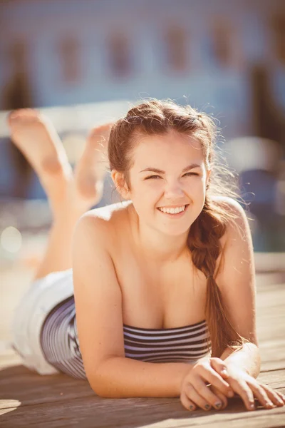 Jonge vrouw verlengd op een kade aan de rand van een meer — Stockfoto