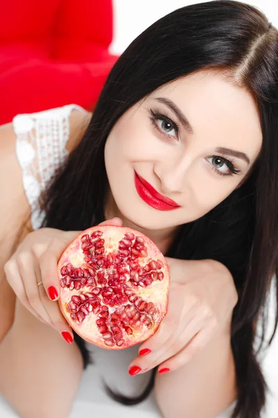 Brunette girl with garnet fruit in studio — Stock Photo, Image