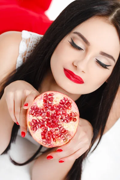 Brunette girl with garnet fruit in studio — Stock Photo, Image