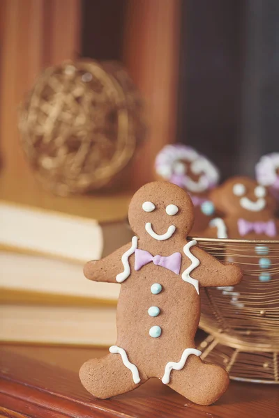 Fun holiday image of smiling gingerbread man with red and white defocused background (christmas dishes with candy) Macro with extremely shallow dof. — Stock Photo, Image