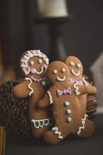 Fun holiday image of smiling gingerbread man with red and white defocused background (christmas dishes with candy) Macro with extremely shallow dof. — Stock Photo, Image