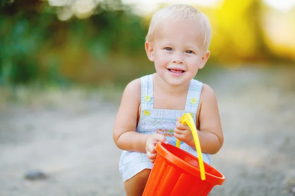 Little smiling boy with toy bucket outdoors — Stock Photo, Image