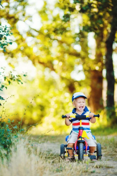 Маленький улыбающийся мальчик на игрушечном велосипеде — стоковое фото