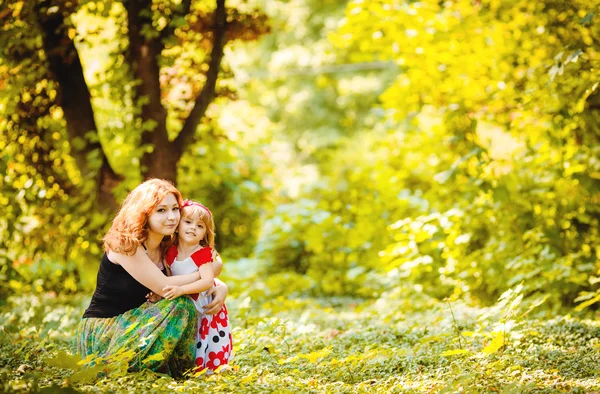 Moeder en dochter spelen in groene zomer park buiten — Stockfoto