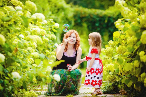 Moeder en dochter spelen in groene zomer park buiten — Stockfoto