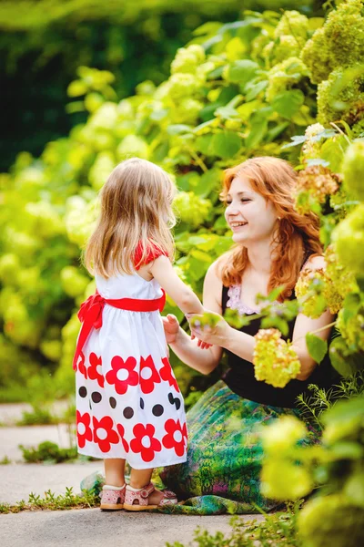Moeder en dochter spelen in groene zomer park buiten — Stockfoto