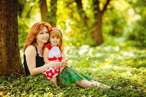 Moeder en dochter spelen in groene zomer park buiten — Stockfoto