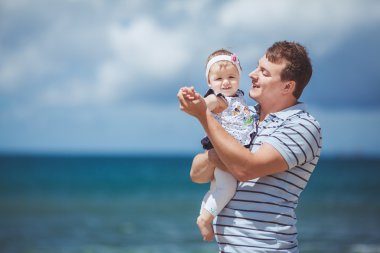 Eğleniyor mavi deniz kenarında yaz aylarında adam ve bebek çocuk mutlu bir aile portresi