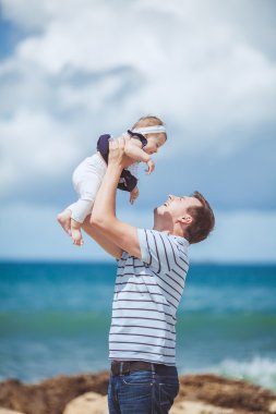 Eğleniyor mavi deniz kenarında yaz aylarında adam ve bebek çocuk mutlu bir aile portresi