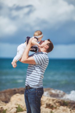 Eğleniyor mavi deniz kenarında yaz aylarında adam ve bebek çocuk mutlu bir aile portresi