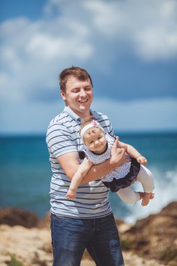 Eğleniyor mavi deniz kenarında yaz aylarında adam ve bebek çocuk mutlu bir aile portresi