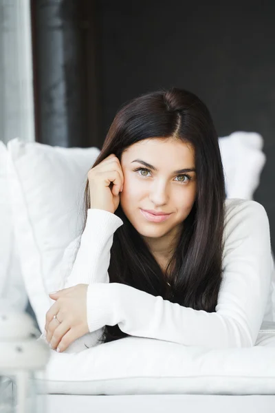 Retrato de una joven hermosa mujer sentada en el sofá en su habitación cerca de la ventana en blanco —  Fotos de Stock