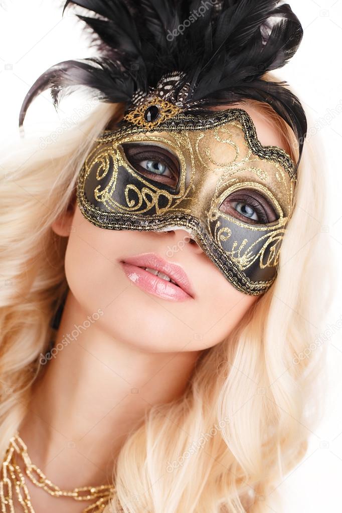 Portrait of Beautiful young blonde woman in black and gold mysterious venetian mask. Fashion photo on white background