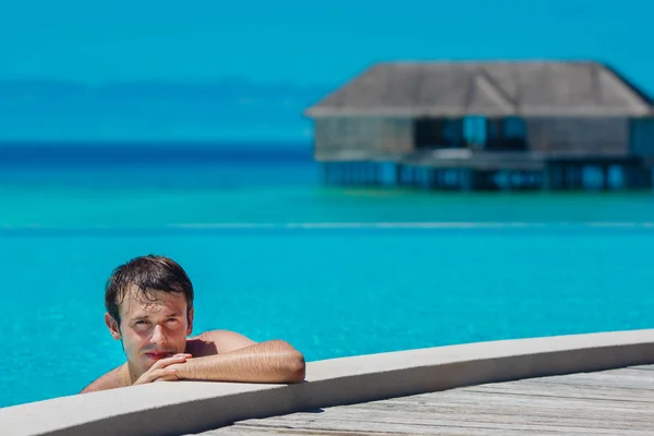 在游泳池和海洋在背景中的年轻男子。马尔代夫 — 图库照片