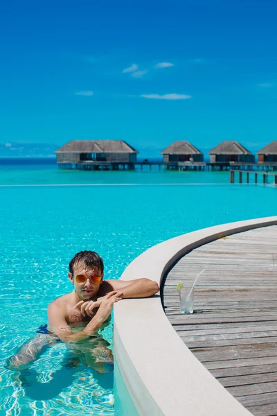 Joven en la piscina y el océano en el fondo. Maldivas — Foto de Stock