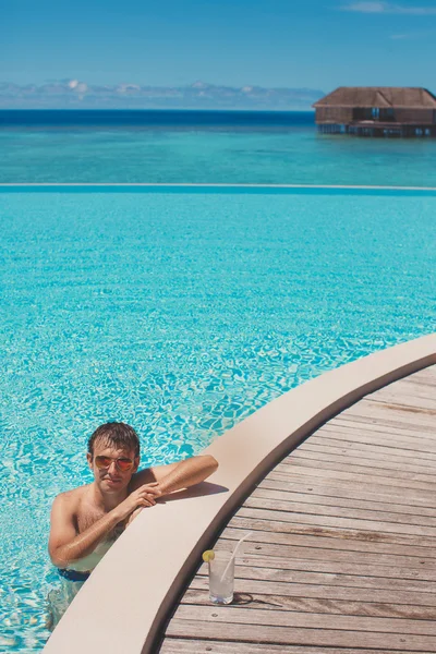 Joven en la piscina y el océano en el fondo. Maldivas — Foto de Stock