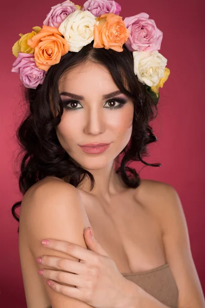 Bela morena jovem com grinalda de flores estúdio tiro fundo rosa — Fotografia de Stock