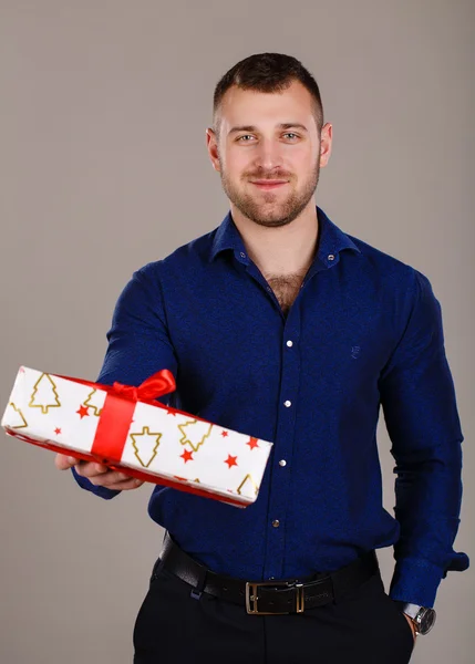 Чоловік з м'язистим торсом з подарунковою коробкою на сірому фоні — стокове фото