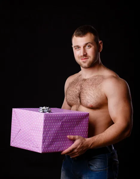肌肉发达的男人抱着圣诞礼物，孤立的黑色的形象 — 图库照片