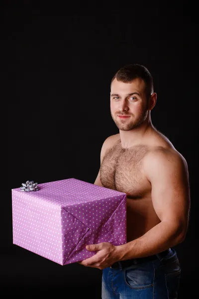 Imagen del hombre musculoso sosteniendo regalos de Navidad, aislado en negro —  Fotos de Stock