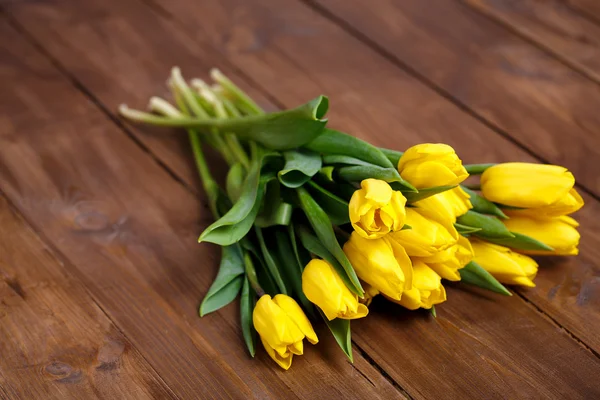 Banco di tulipani gialli sdraiato su tavole di legno — Foto Stock