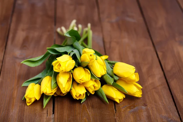 Banco di tulipani gialli sdraiato su tavole di legno — Foto Stock
