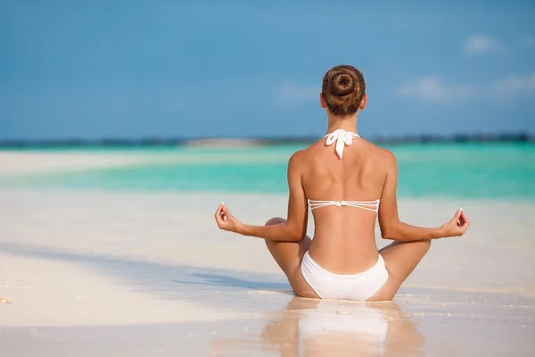 Portret van een jonge vrouw doen yoga oefeningen op tropische Maldivische strand in de buurt van ocean — Stockfoto