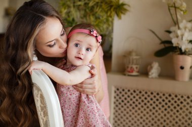 haome iç penceresinde yanında onun bebek kız oynamaktan mutlu genç cazip anne portresi. Anne ve kızı üzerinde pembe elbiseler