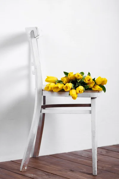 Hermosos tulipanes amarillos brillantes en Bodegón acostado en silla blanca antigua — Foto de Stock