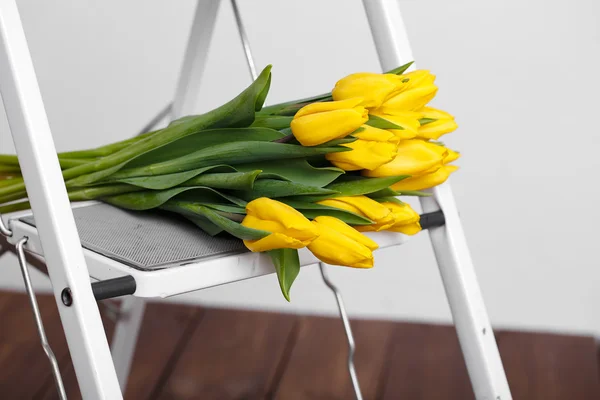 Beautiful bright yellow tulips More lying on sofa white stairs — Stock Photo, Image