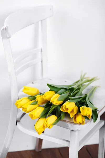 Schöne leuchtend gelbe Tulpen im Stillleben auf antikem weißen Stuhl liegend — Stockfoto