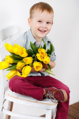 gülen çocuk portre sarı lale çiçekleri beyaz duvara yakın duran elinde bir buket