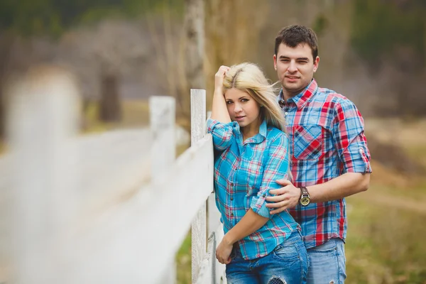 Retrato de feliz pareja joven con camisetas que se divierten al aire libre cerca de la cerca en el parque —  Fotos de Stock