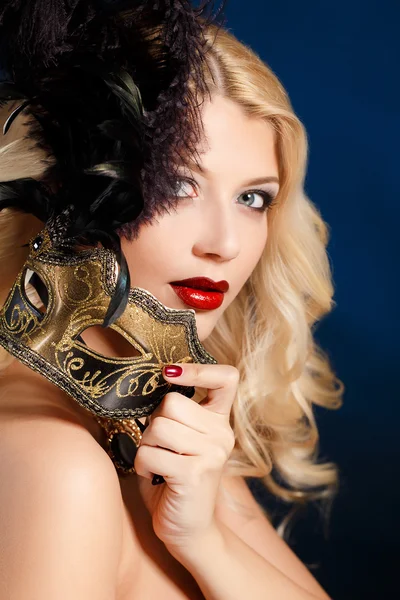 Színházi maszk az arcán sötét háttér előtt egy gyönyörű fiatal szőke nő portréja — Stock Fotó