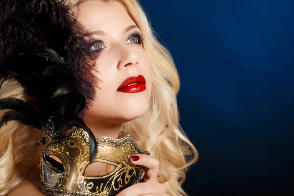güzel genç sarışın bir kadın tiyatro maskesi yüzünde koyu arka plan üzerinde portresi