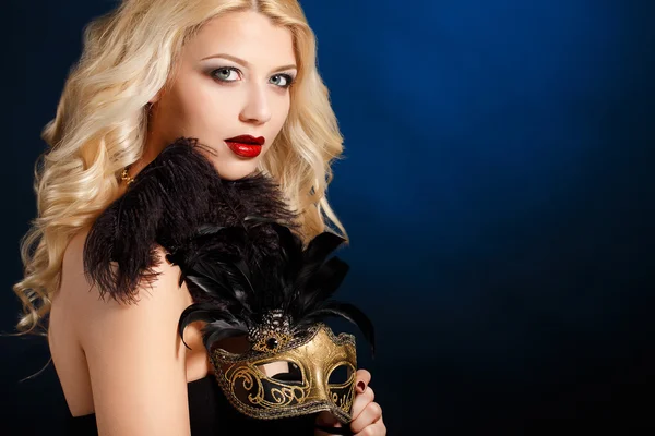 Portrait of a beautiful young blond woman with theatrical mask on his face on a dark background — Stock Photo, Image