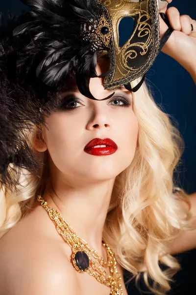 Portrait of a beautiful young blond woman with theatrical mask on his face on a dark background — Stock Photo, Image