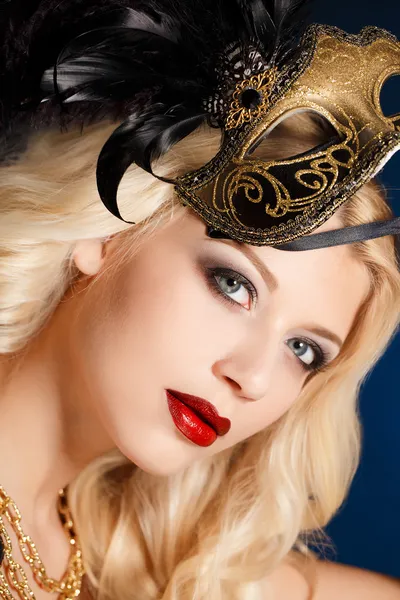 Portrait of a beautiful young blond woman with theatrical mask on his face on a dark background — Stock Photo, Image