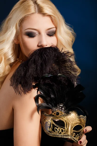Porträt einer schönen jungen blonden Frau mit Theatermaske auf dem Gesicht vor dunklem Hintergrund — Stockfoto