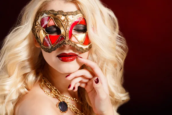 Retrato de una hermosa joven rubia con máscara teatral en la cara sobre un fondo oscuro — Foto de Stock