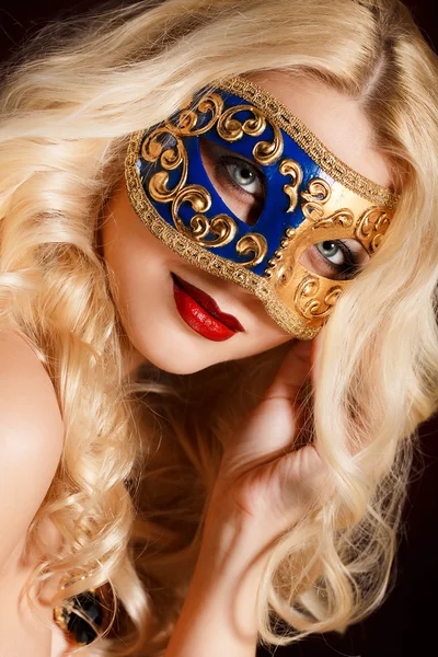 Portrait of a beautiful young blond woman with theatrical mask on his face on a dark background — Stock Photo, Image