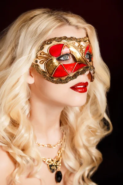 Porträtt av en vacker ung blond kvinna med teatraliska mask i ansiktet på en mörk bakgrund — Stockfoto
