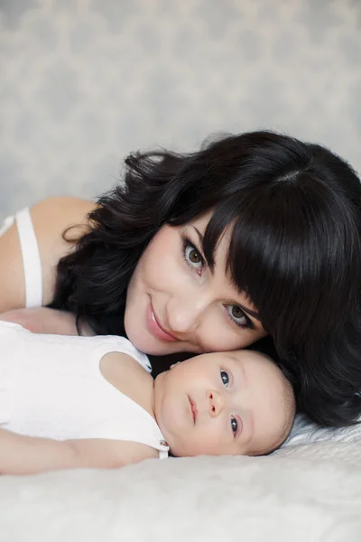 Portrait of happy young attractive mother with her baby ion hands n home interior — Stock Photo, Image