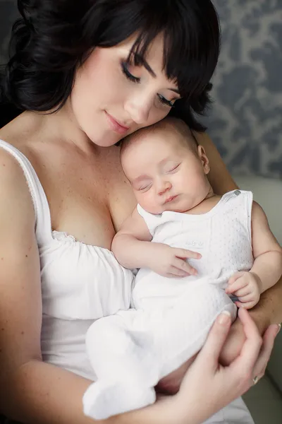 Retrato de feliz jovem atraente mãe com seu bebê íon mãos n casa interior — Fotografia de Stock