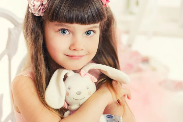 Little girl with soft toy sitting on a chair — Stock Photo, Image