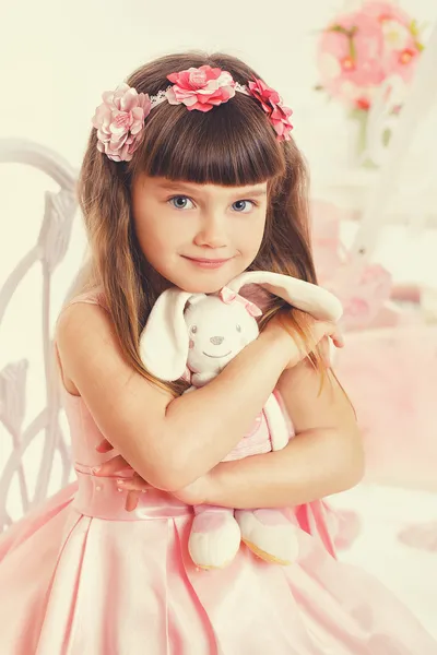 Маленькая девочка с мягкой игрушкой сидит на стуле — стоковое фото