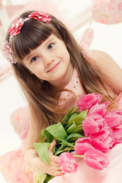 Gros plan portrait de petite adorable fille tenant des tulipes roses dans ses mains . — Photo