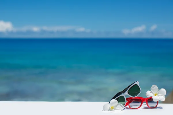 Two pairs of sunglasses on background of ocean