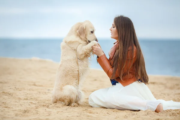 Flicka med hund på stranden — Stockfoto