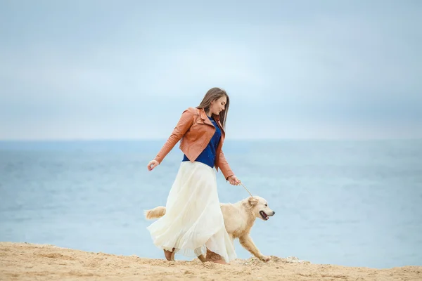 Flicka med hund på stranden — Stockfoto